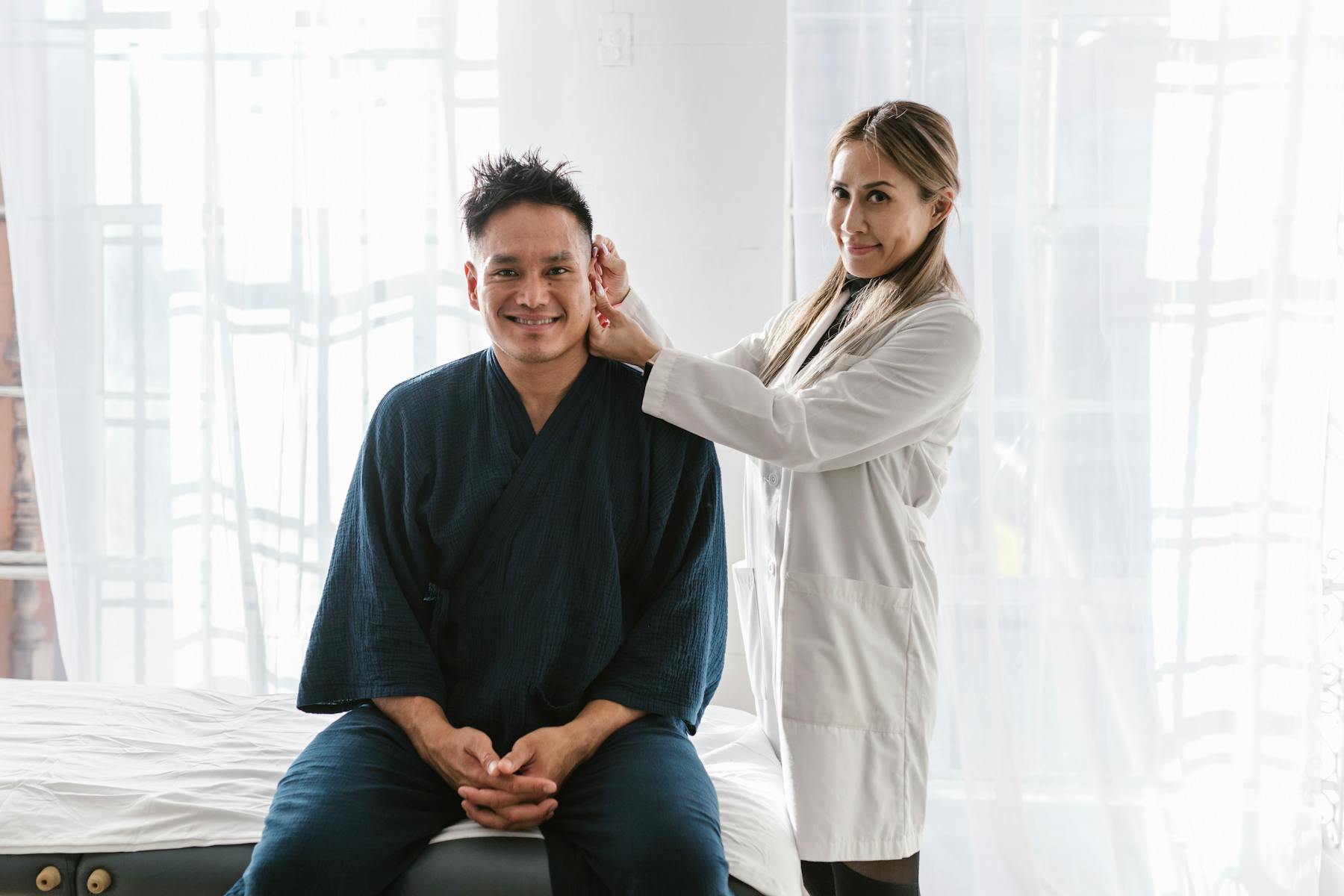 Physician examining a smiling patient in a bright clinic room